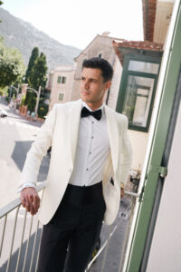 Groom in white tuxedo posing for editorial wedding portrait in Mallorca