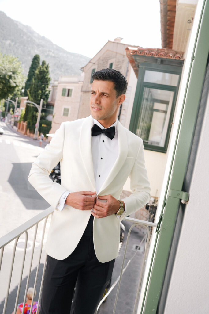 groom in white tuxedo on balcony in Soller town mallorca wedding photographer